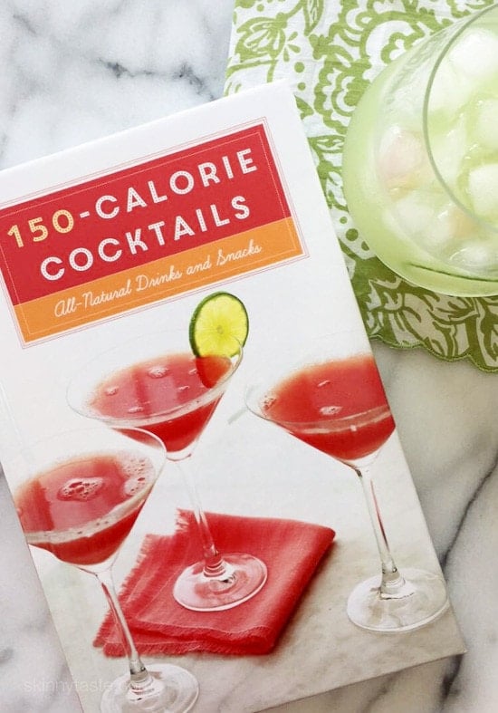 A book titled 150-calorie Cocktails and a glass filled with Basil Cucumber Cooler cocktail with ice