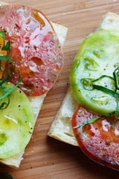 A juicy open faced summer tomato sandwich on crusty bread drizzled with extra virgin olive oil, a chiffonade of fresh basil, salt and fresh ground pepper. Simplicity at it's best!