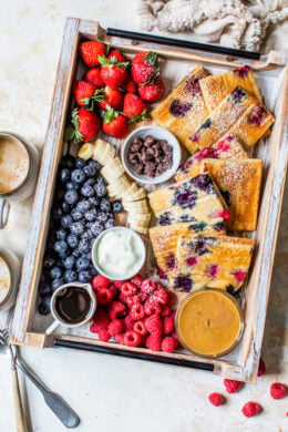 sheet pan pancakes on a try with berries and toppings.